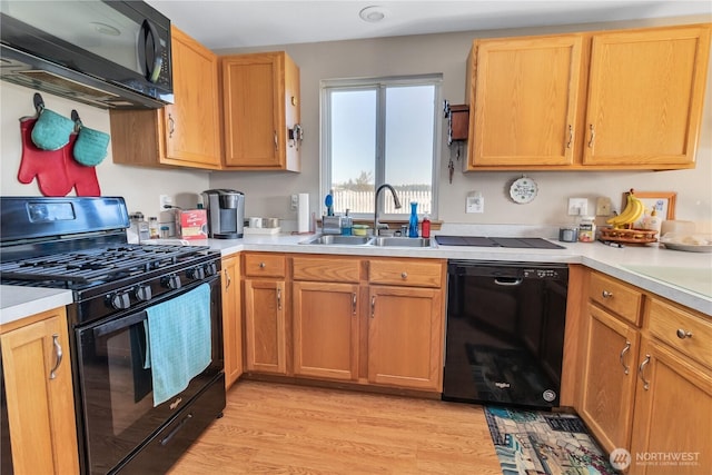 kitchen featuring black appliances, light wood-style flooring, light countertops, and a sink