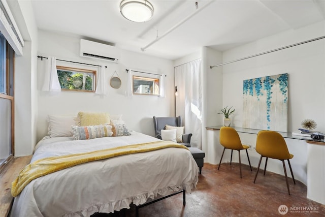 bedroom featuring an AC wall unit and concrete floors