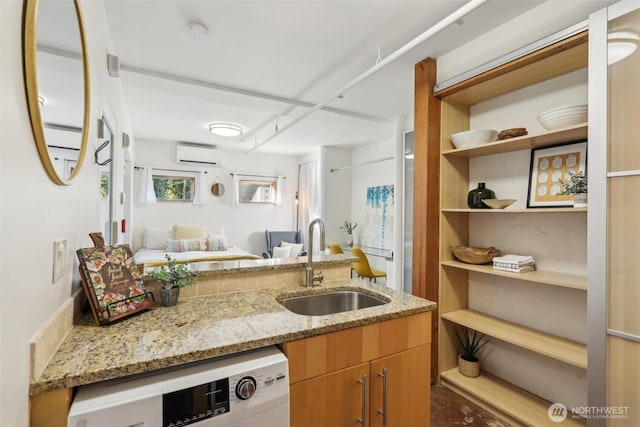 kitchen featuring light stone countertops, open shelves, a sink, an AC wall unit, and open floor plan