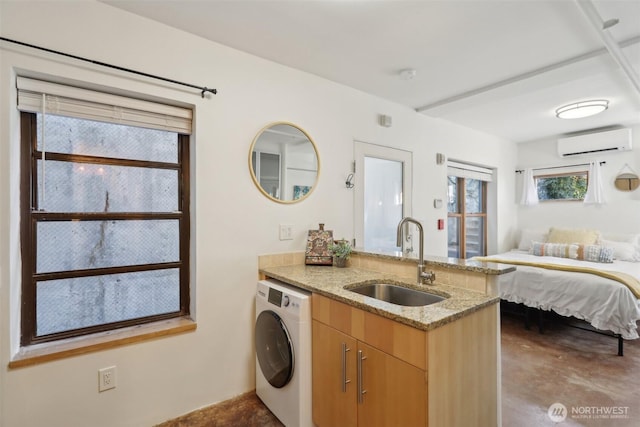 interior space featuring a wall unit AC, light stone countertops, washer / dryer, a sink, and open floor plan