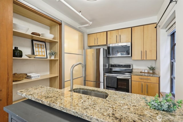 kitchen with light stone counters, open shelves, stainless steel appliances, and a sink