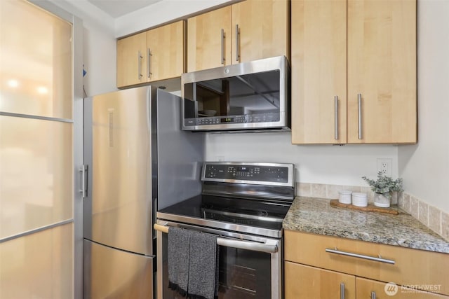 kitchen with stainless steel appliances, light stone countertops, and light brown cabinets