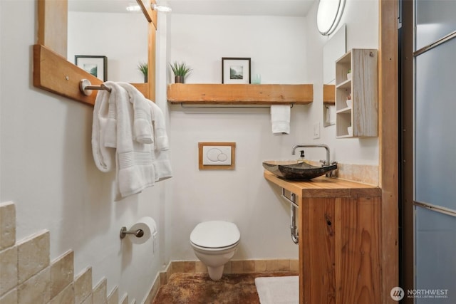 half bathroom featuring a sink, baseboards, and toilet