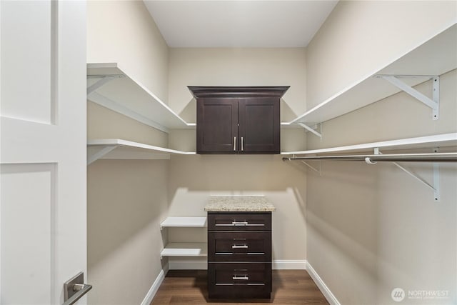 walk in closet with dark wood-type flooring