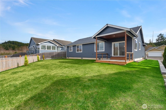 back of property featuring a wooden deck, a lawn, and fence