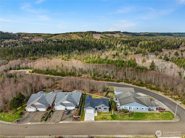 drone / aerial view featuring a wooded view and a residential view