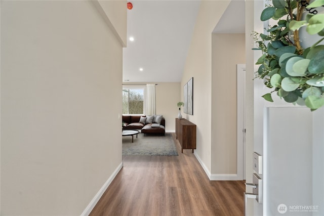 hallway with recessed lighting, baseboards, a high ceiling, and wood finished floors