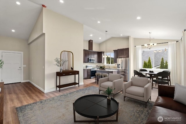 living room with high vaulted ceiling, wood finished floors, recessed lighting, baseboards, and a chandelier