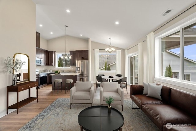 living room featuring visible vents, recessed lighting, light wood-style floors, lofted ceiling, and a chandelier