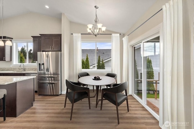 dining space with light wood finished floors, a notable chandelier, recessed lighting, and vaulted ceiling