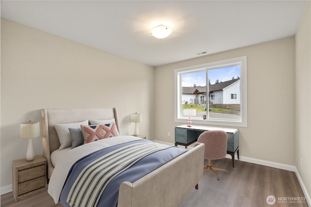 bedroom featuring visible vents, baseboards, and wood finished floors