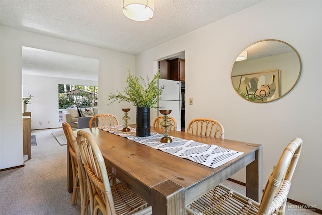 dining area with light carpet, a textured ceiling, and baseboards