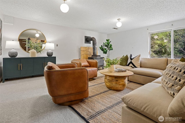 living room with visible vents, light carpet, a textured ceiling, and a wood stove