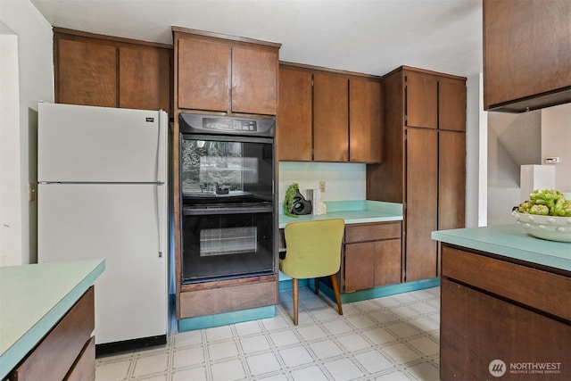 kitchen featuring light floors, light countertops, dobule oven black, and freestanding refrigerator