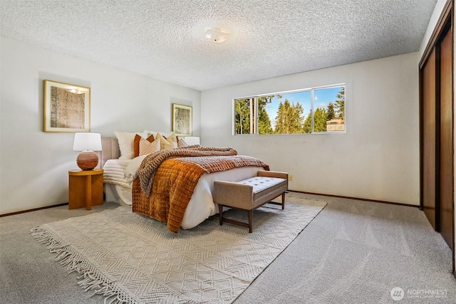 bedroom featuring light colored carpet, a textured ceiling, and baseboards