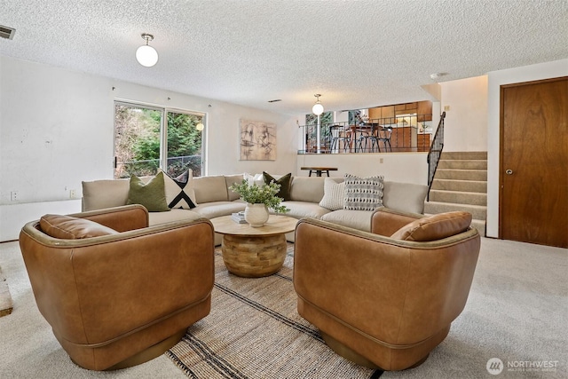 living area featuring stairway, a textured ceiling, visible vents, and carpet floors