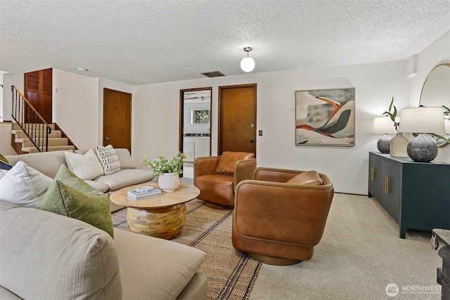 living room with visible vents, stairway, light colored carpet, a textured ceiling, and separate washer and dryer