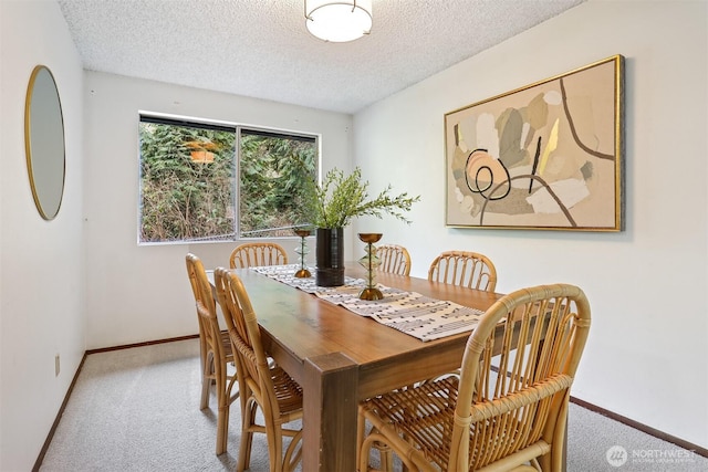 dining area with carpet flooring, a textured ceiling, and baseboards