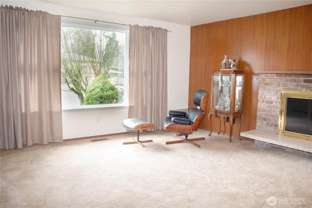 sitting room featuring wood walls, a fireplace, carpet flooring, and visible vents