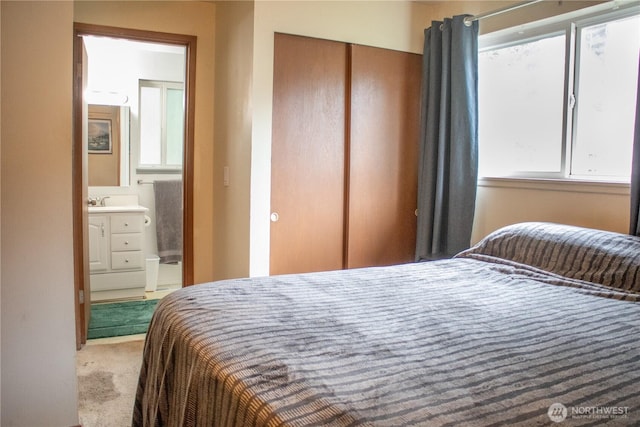 bedroom featuring carpet floors, a closet, and ensuite bath