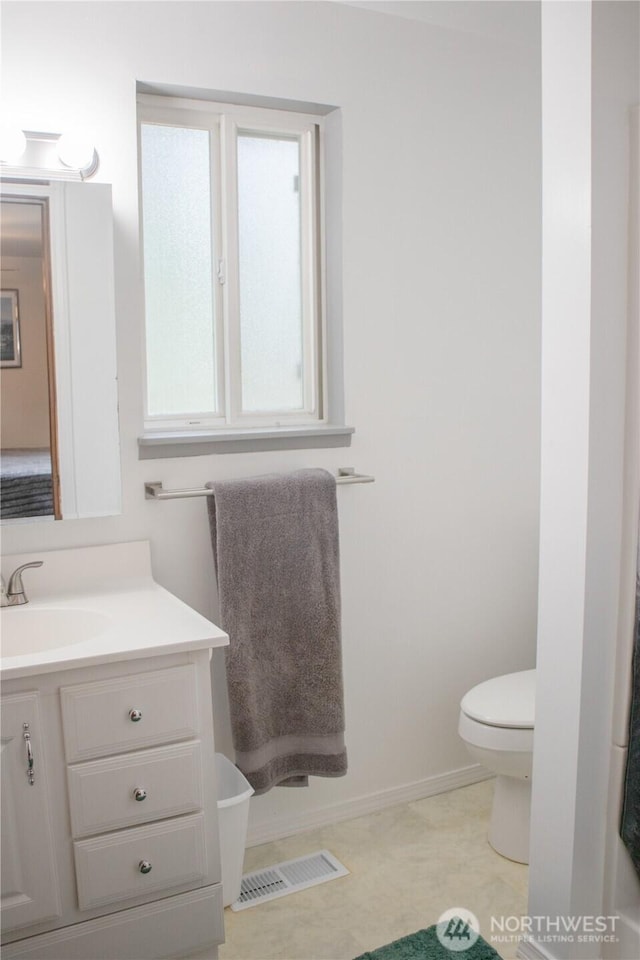 bathroom with baseboards, visible vents, vanity, and toilet