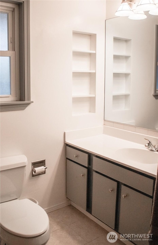 bathroom featuring baseboards, vanity, toilet, and tile patterned floors