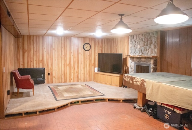 interior space featuring a paneled ceiling, wood walls, and a fireplace