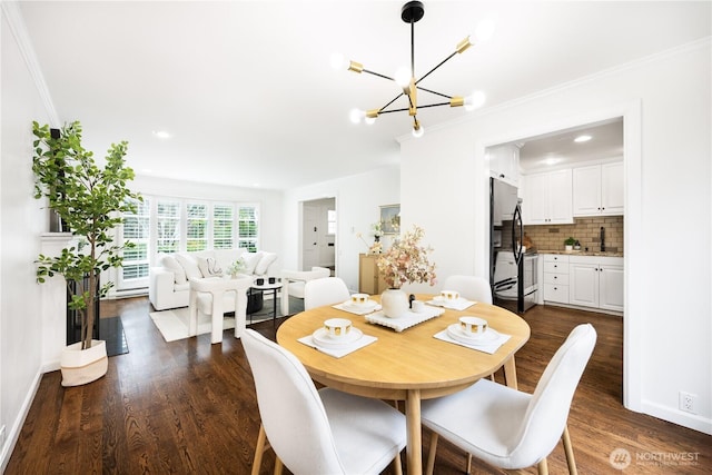 dining space with a notable chandelier, baseboards, dark wood finished floors, and crown molding