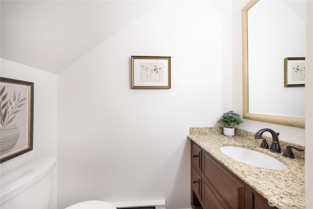 bathroom with a baseboard radiator, vaulted ceiling, vanity, and toilet