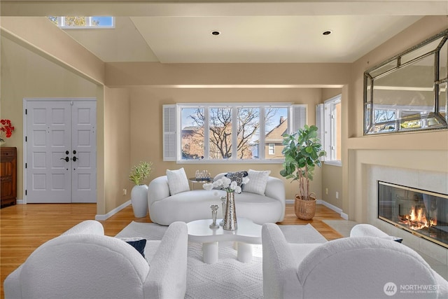 living room featuring recessed lighting, a fireplace, baseboards, and wood finished floors