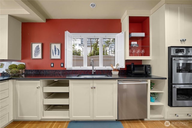 kitchen featuring a sink, open shelves, dark countertops, stainless steel appliances, and light wood finished floors