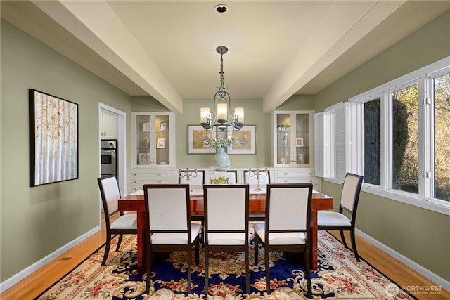 dining space with an inviting chandelier, light wood-type flooring, and baseboards