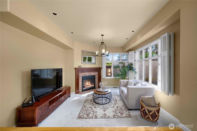 carpeted living room with a brick fireplace, baseboards, and a chandelier