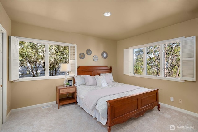 bedroom featuring baseboards, multiple windows, and light colored carpet