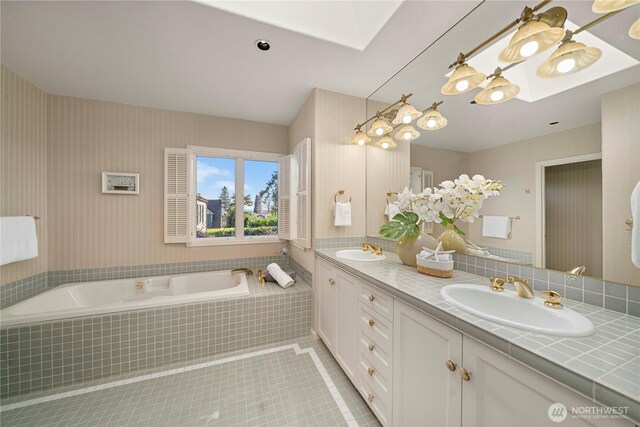 full bath featuring a sink, a garden tub, double vanity, and tile patterned flooring