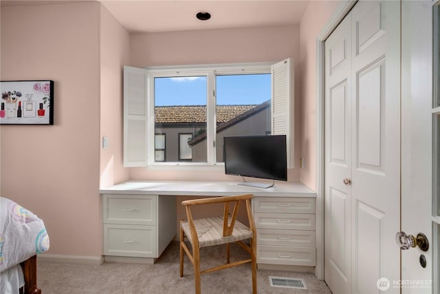 bedroom with light carpet, visible vents, built in study area, and baseboards