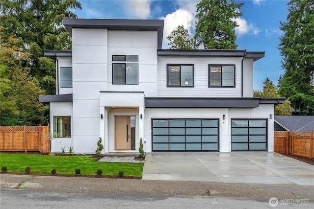 contemporary house with stucco siding, a front lawn, fence, concrete driveway, and an attached garage