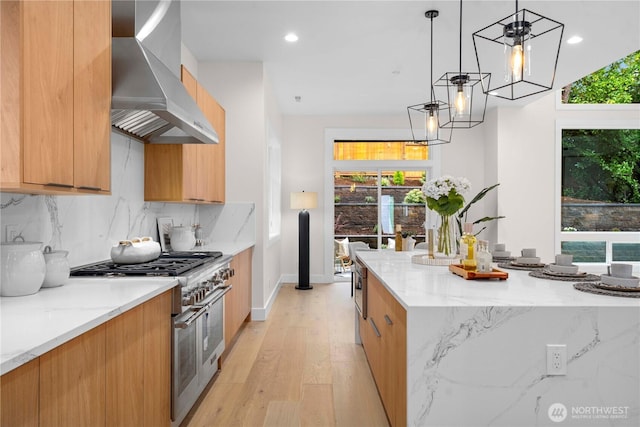 kitchen featuring light wood-type flooring, decorative backsplash, stainless steel stove, modern cabinets, and wall chimney exhaust hood