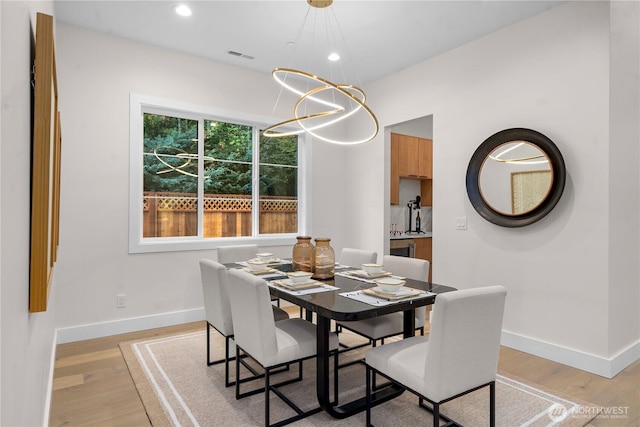 dining room featuring a notable chandelier, baseboards, light wood-type flooring, and visible vents