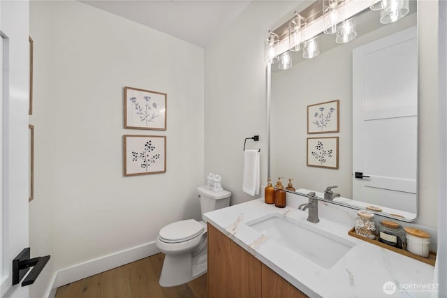 half bathroom featuring baseboards, toilet, wood finished floors, and vanity