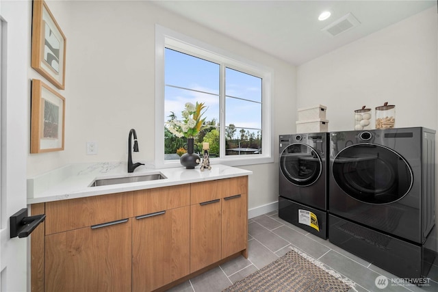 laundry room featuring visible vents, cabinet space, tile patterned floors, washer and dryer, and a sink