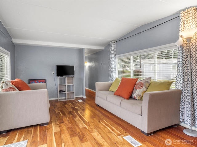 living room featuring lofted ceiling, wood finished floors, visible vents, and baseboards