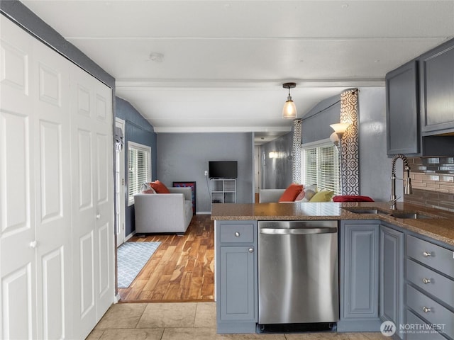 kitchen featuring lofted ceiling with beams, stainless steel dishwasher, open floor plan, a sink, and a peninsula