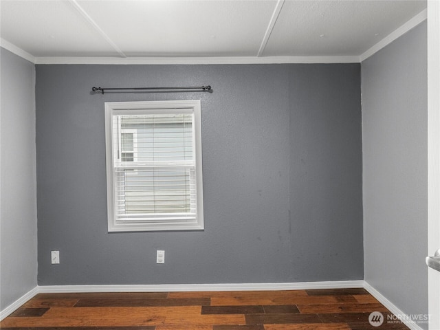 spare room with dark wood-style floors, crown molding, and baseboards