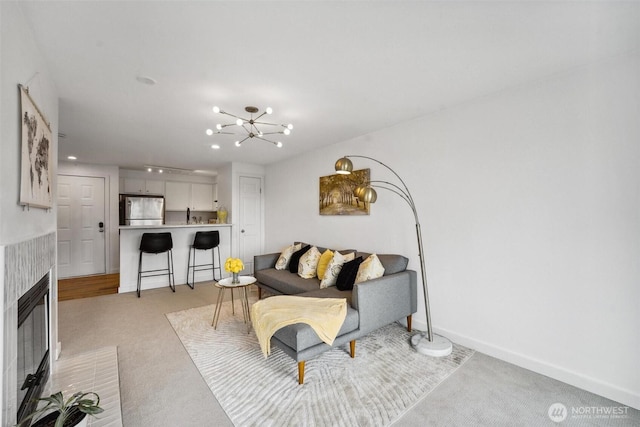 living area with recessed lighting, light colored carpet, an inviting chandelier, a tile fireplace, and baseboards