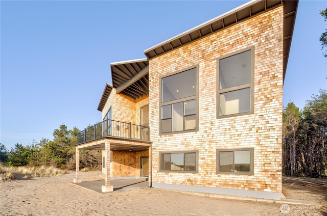 exterior space featuring brick siding, a patio, and a balcony