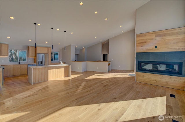 kitchen with modern cabinets, stainless steel appliances, light wood-style floors, light brown cabinets, and a fireplace