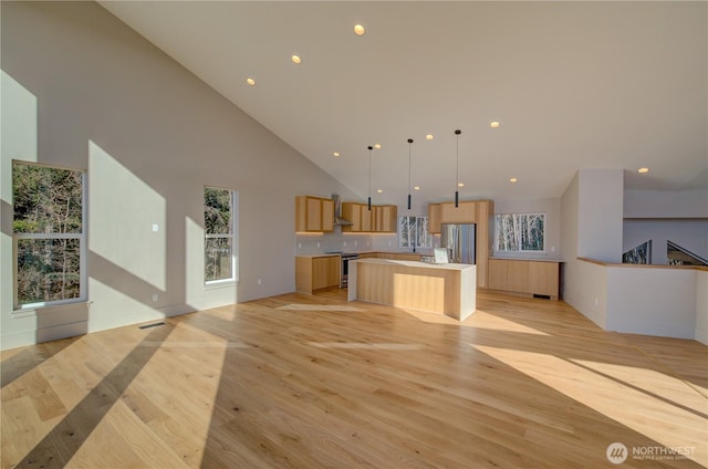 unfurnished living room featuring a towering ceiling, light wood finished floors, visible vents, and recessed lighting