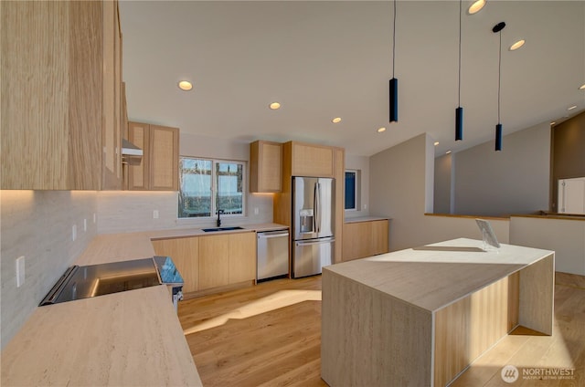 kitchen with light brown cabinetry, appliances with stainless steel finishes, light wood-type flooring, and a sink