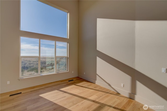 empty room with visible vents, baseboards, and wood finished floors